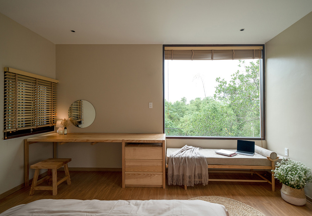 Phòng ngủ thiết kế đơn giản có cửa sổ rộng nhìn ra ngoài cây xanh.